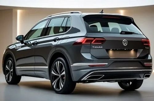 На изображении серый кроссовер Volkswagen Tiguan. Вид сзади, видны задние фонари и эмблема. Автомобиль стоит в светлом помещении.